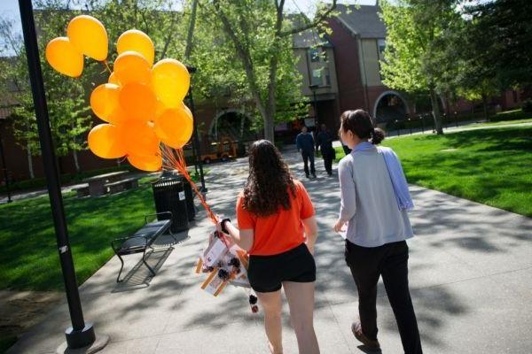 students walk on campus with balloons