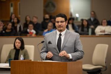 Man in grey suit speaks in courtroom 